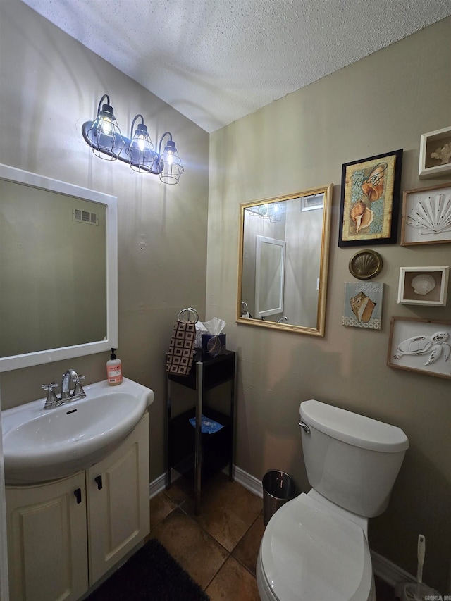 bathroom with tile patterned flooring, vanity, a textured ceiling, and toilet