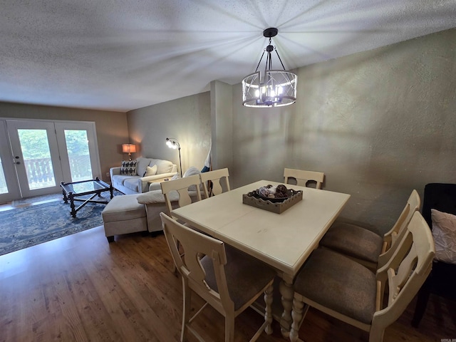 dining area with french doors, dark hardwood / wood-style flooring, a notable chandelier, and a textured ceiling