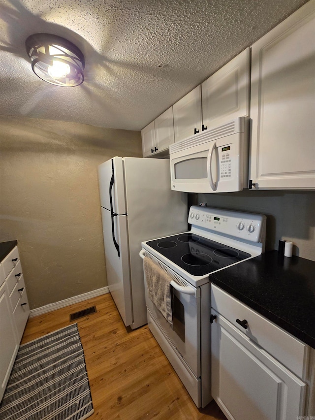 kitchen featuring white appliances, white cabinetry, a textured ceiling, and light hardwood / wood-style floors