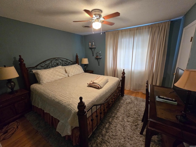 bedroom with a textured ceiling, ceiling fan, and dark hardwood / wood-style floors