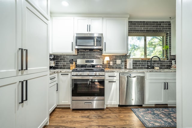 kitchen with light stone counters, dark wood-type flooring, sink, white cabinetry, and stainless steel appliances