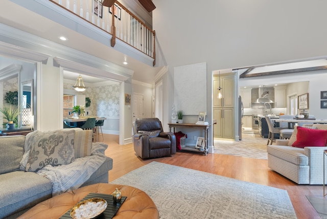 living room featuring ornamental molding, a high ceiling, and light hardwood / wood-style floors