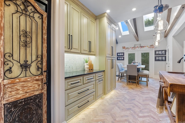 kitchen with cream cabinetry, light parquet flooring, pendant lighting, vaulted ceiling with skylight, and french doors