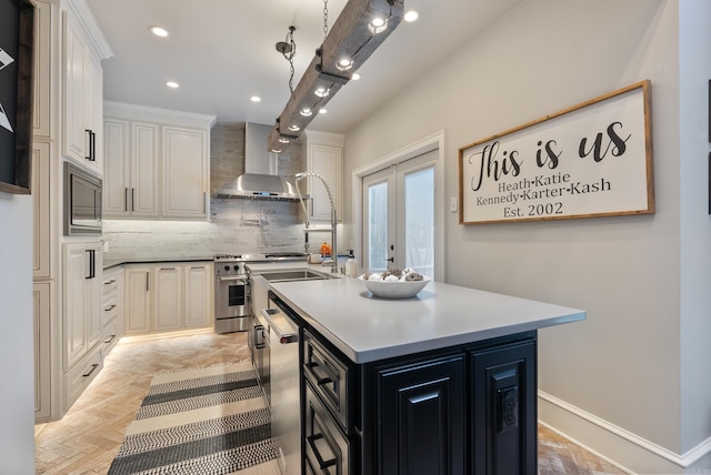 kitchen featuring decorative backsplash, white cabinets, wall chimney exhaust hood, stainless steel appliances, and a center island with sink