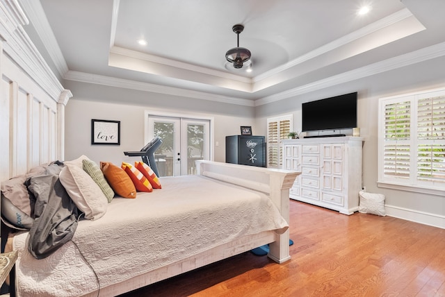 bedroom with wood-type flooring, a tray ceiling, crown molding, and access to exterior