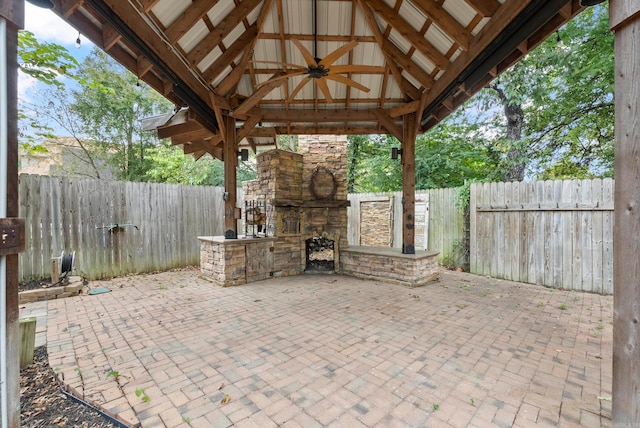 view of patio / terrace with ceiling fan, a gazebo, and an outdoor stone fireplace