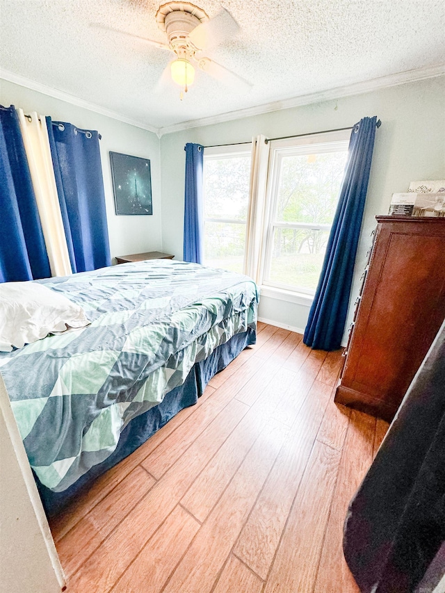 bedroom with ceiling fan, ornamental molding, a textured ceiling, and hardwood / wood-style floors