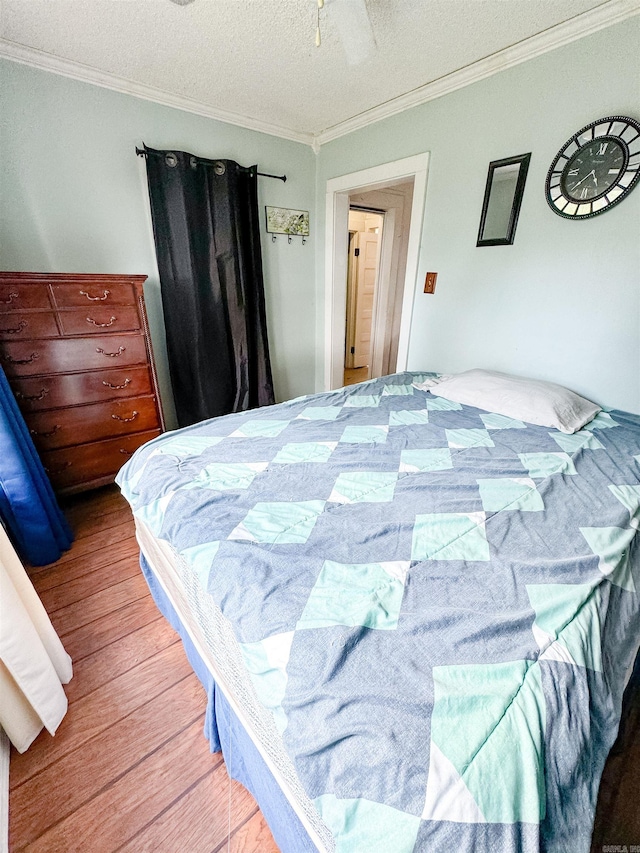 bedroom with a textured ceiling, ornamental molding, hardwood / wood-style floors, and ceiling fan