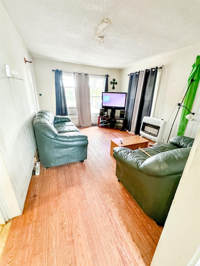 living room featuring heating unit, a textured ceiling, and hardwood / wood-style flooring