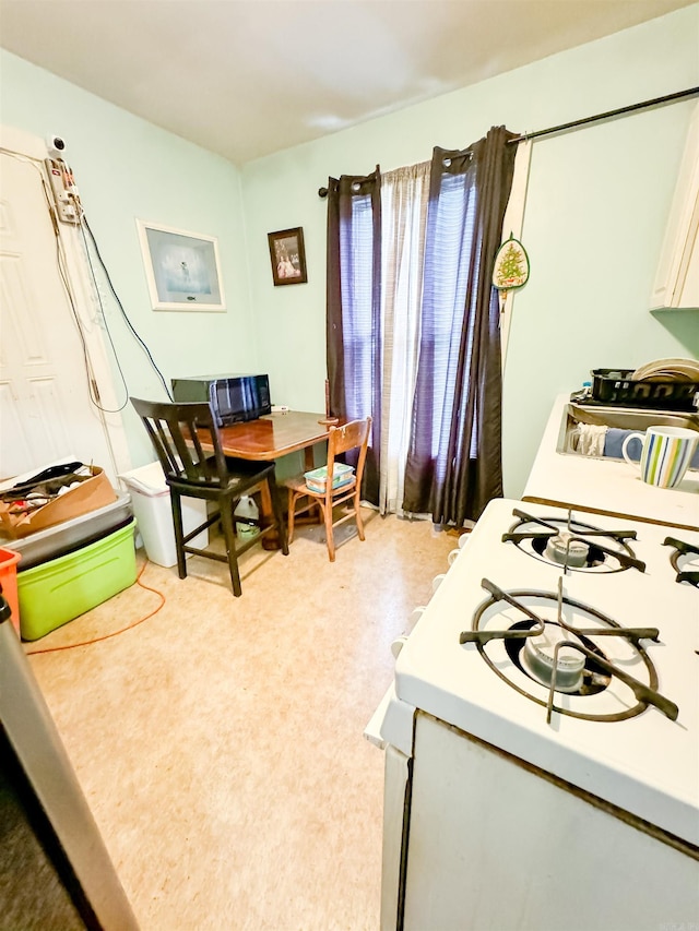 kitchen featuring light carpet, white cabinets, and white gas range oven