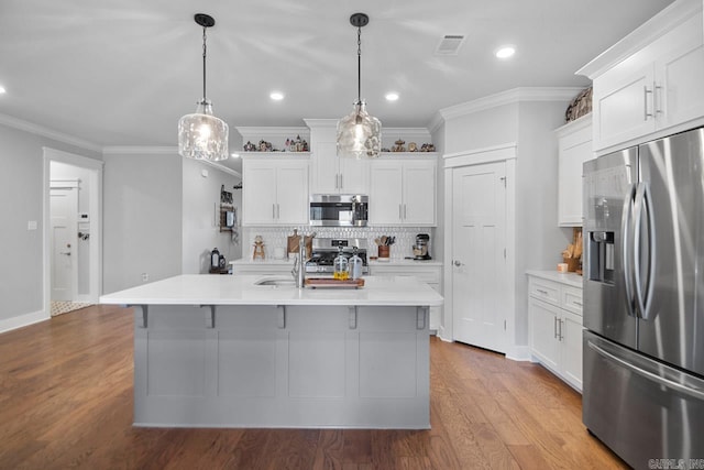 kitchen with pendant lighting, light wood-type flooring, an island with sink, white cabinetry, and appliances with stainless steel finishes