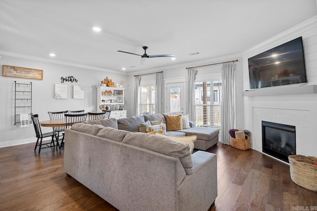 living room featuring crown molding, dark hardwood / wood-style floors, ceiling fan, and a brick fireplace