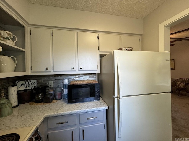 kitchen with a textured ceiling, range, white fridge, and tasteful backsplash