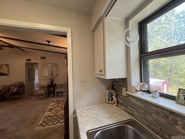 kitchen featuring vaulted ceiling with beams, a textured ceiling, plenty of natural light, and carpet