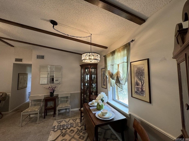 dining room featuring a textured ceiling, carpet flooring, and beamed ceiling