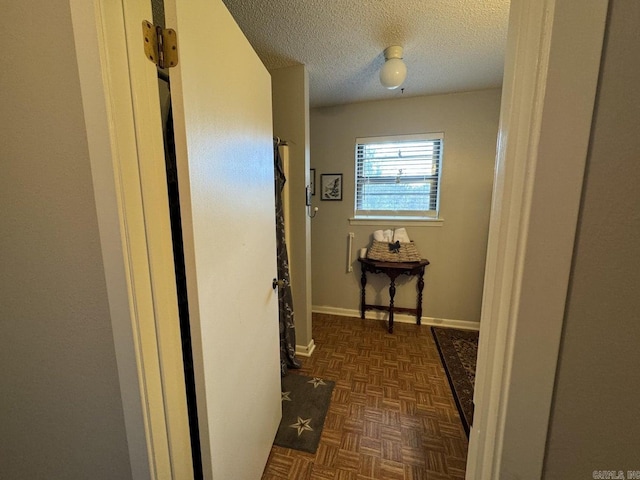 hallway with a textured ceiling and dark parquet flooring