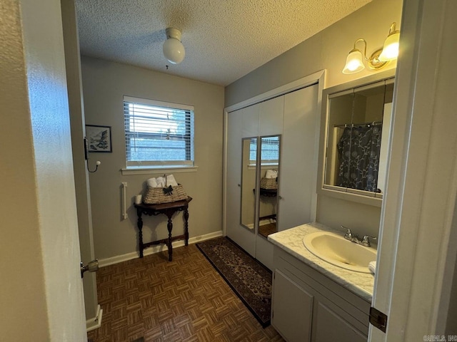 bathroom featuring a textured ceiling, parquet floors, and vanity