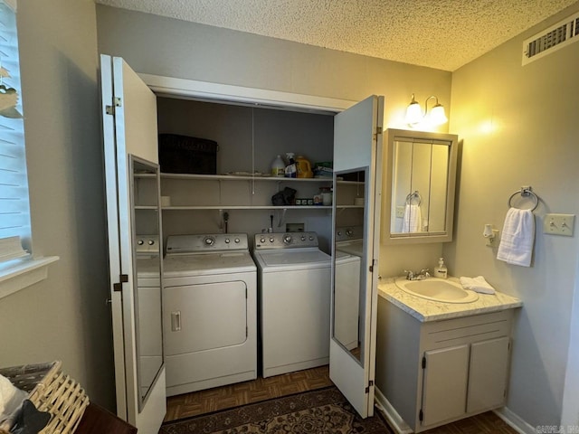 laundry area featuring a textured ceiling, dark parquet floors, sink, and washing machine and dryer