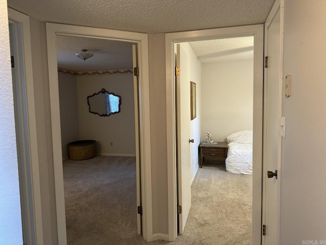 hall with light carpet and a textured ceiling