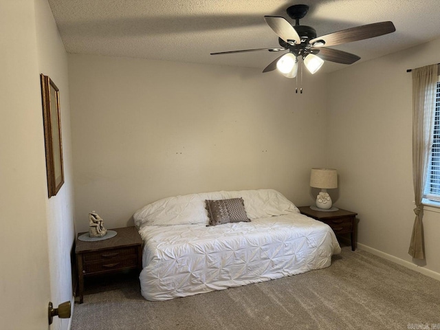 bedroom featuring multiple windows, ceiling fan, carpet floors, and a textured ceiling