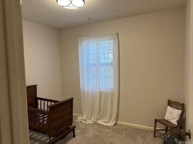 bedroom featuring carpet floors, a crib, and a textured ceiling