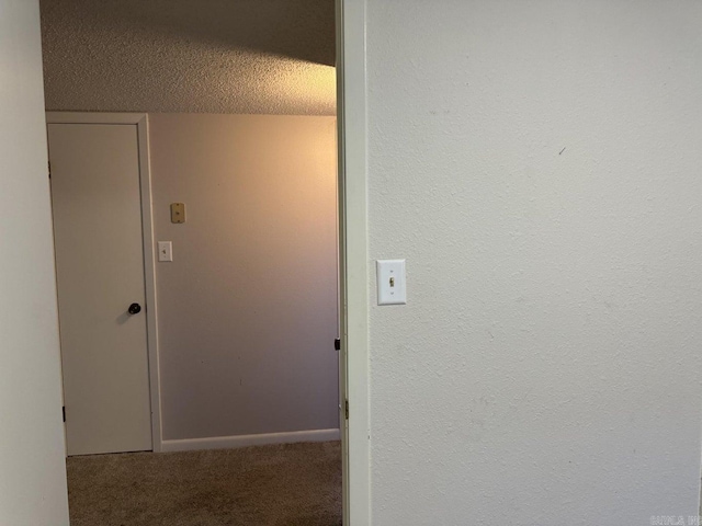 corridor with a textured ceiling and carpet floors