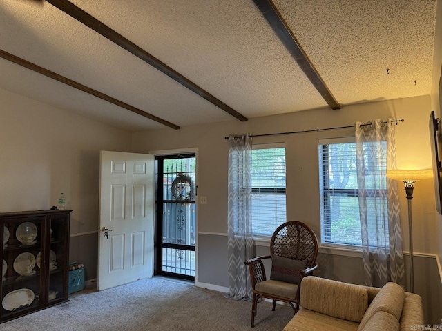 living area featuring carpet floors, a healthy amount of sunlight, a textured ceiling, and beam ceiling