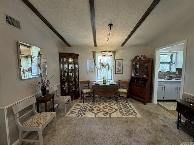 carpeted dining room with a textured ceiling, beam ceiling, sink, and a notable chandelier