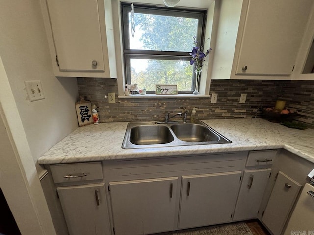 kitchen featuring sink, light stone counters, and tasteful backsplash