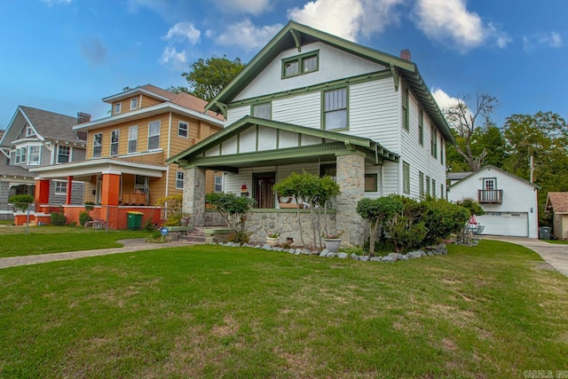 view of front of home featuring covered porch, a front yard, an outbuilding, and a garage