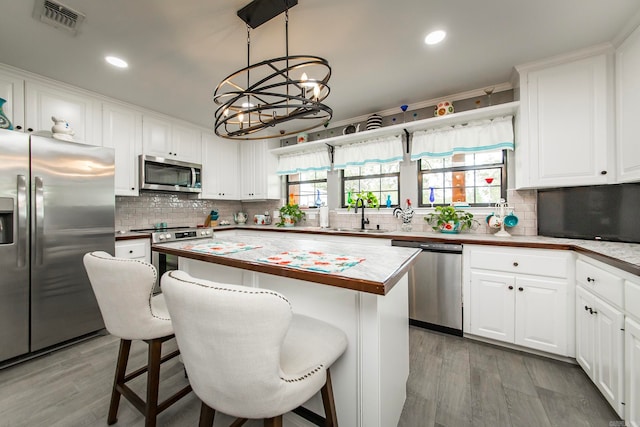 kitchen with appliances with stainless steel finishes, a center island, decorative light fixtures, wood counters, and a notable chandelier