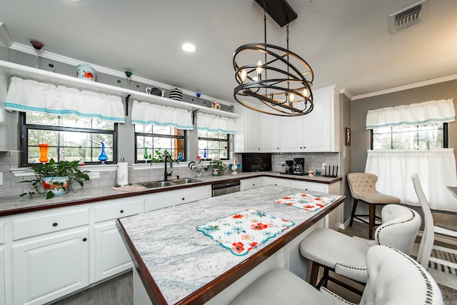 kitchen with decorative backsplash, white cabinetry, ornamental molding, and sink