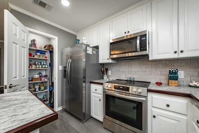 kitchen featuring ornamental molding, white cabinetry, appliances with stainless steel finishes, and tasteful backsplash