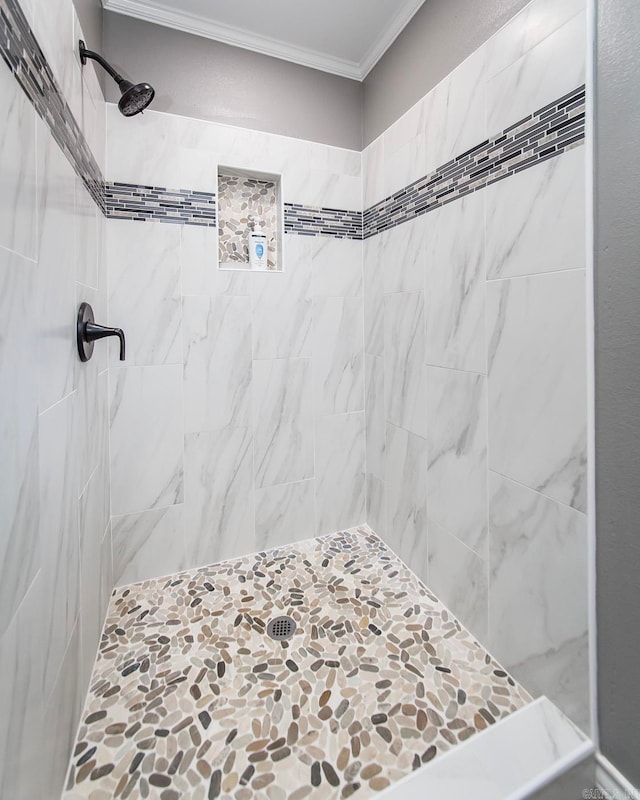 bathroom with a tile shower and ornamental molding