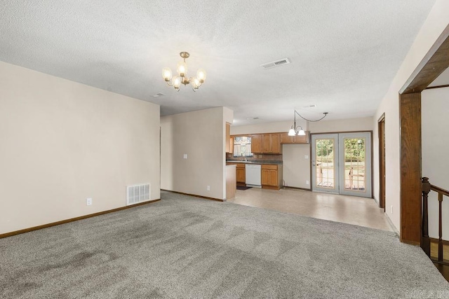 unfurnished living room with light carpet, a chandelier, and a textured ceiling