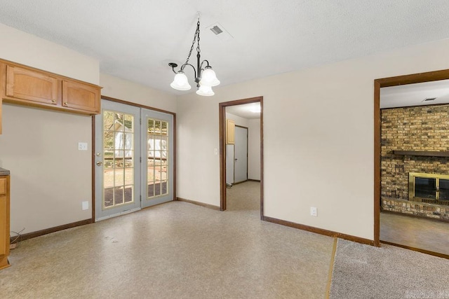 unfurnished dining area with a textured ceiling, a fireplace, and a chandelier