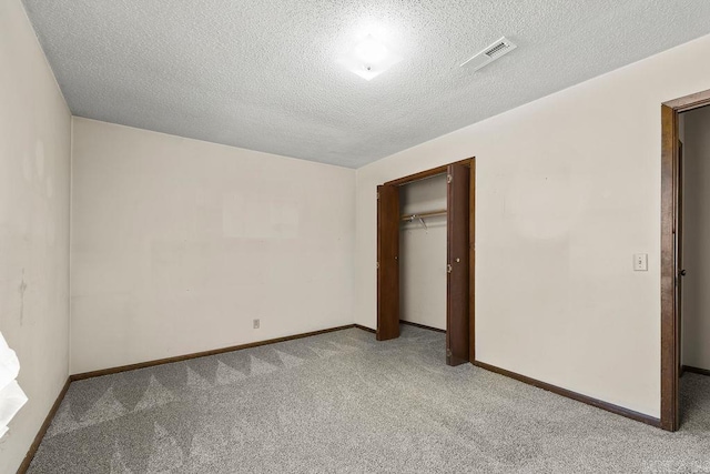 unfurnished bedroom with light carpet, a textured ceiling, and a closet