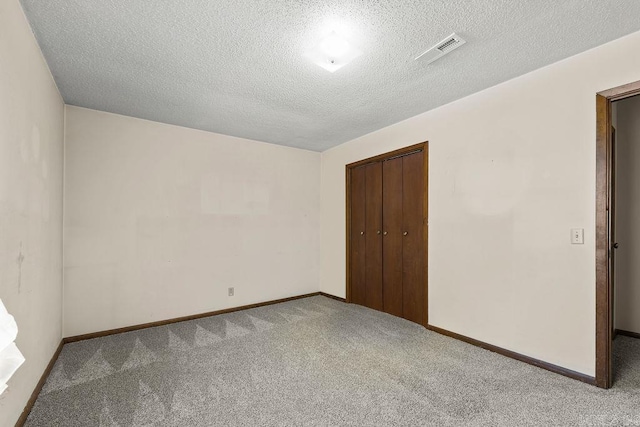 unfurnished bedroom with a textured ceiling, carpet flooring, and a closet