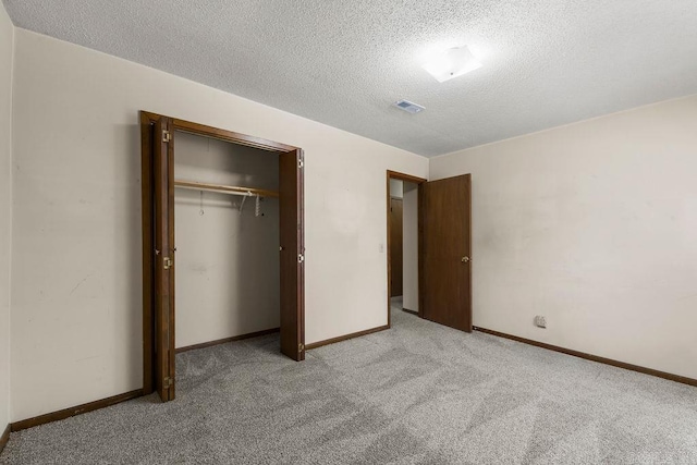 unfurnished bedroom featuring a textured ceiling, light carpet, and a closet