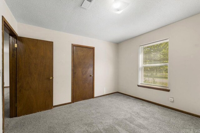 unfurnished bedroom featuring carpet, a closet, and a textured ceiling