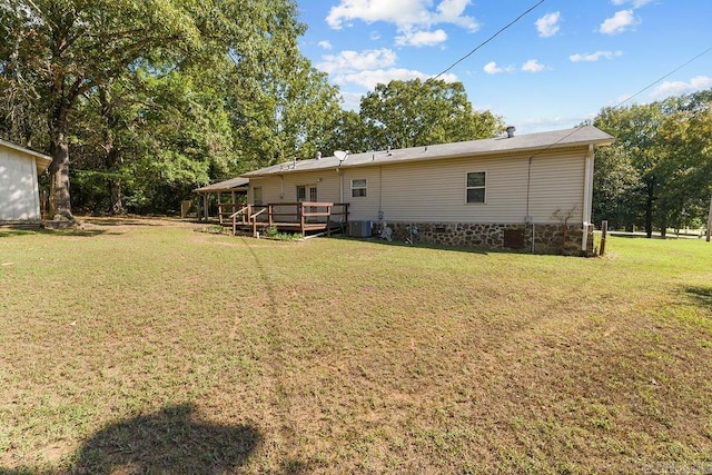 back of property with a lawn, central AC unit, and a deck