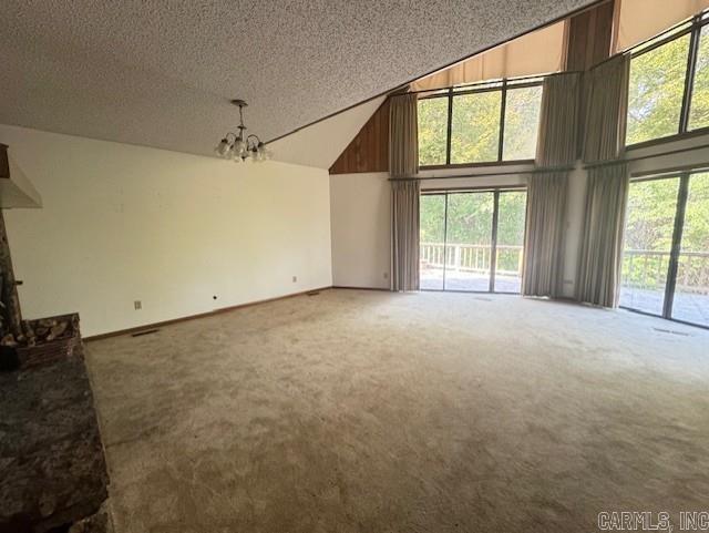 unfurnished living room featuring a chandelier, a textured ceiling, and carpet floors