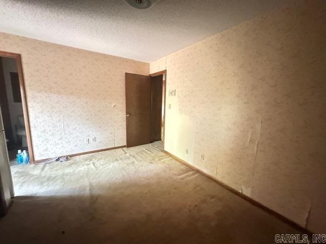 carpeted empty room with a textured ceiling