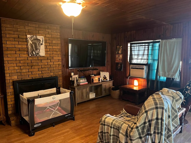 living room featuring a brick fireplace, wood ceiling, wood walls, and hardwood / wood-style floors