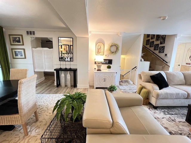 living room with light wood-type flooring, crown molding, and an inviting chandelier