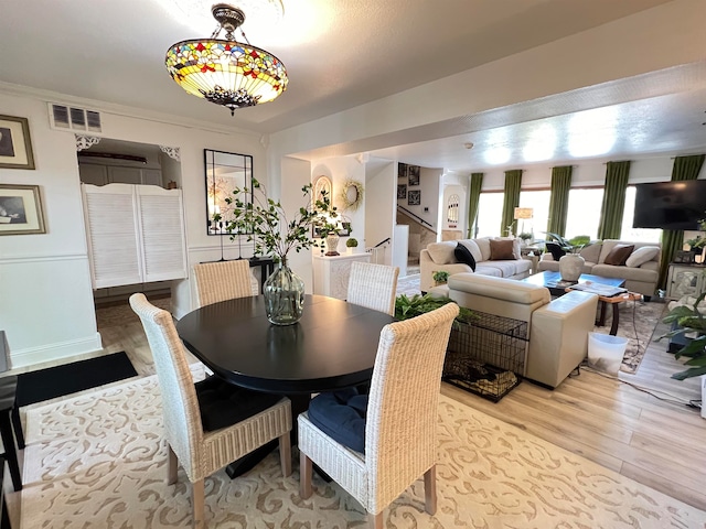 dining space with light wood-type flooring and crown molding