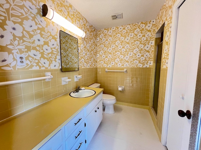 bathroom featuring vanity, an enclosed shower, a textured ceiling, tile walls, and toilet