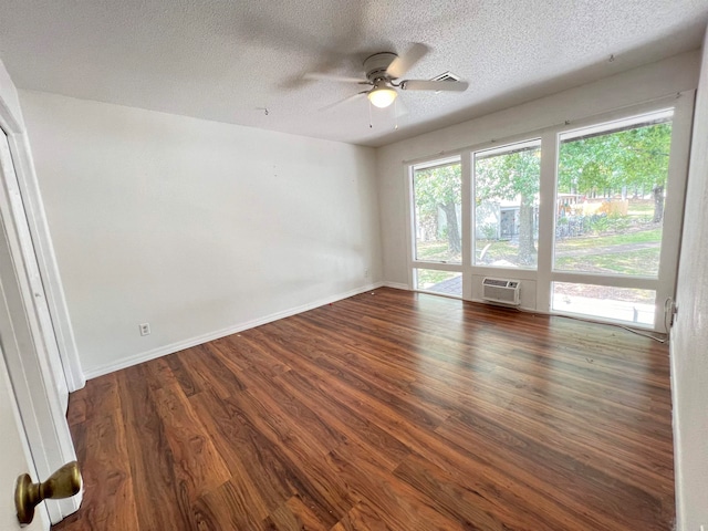 empty room with a textured ceiling, a wall mounted AC, dark wood-type flooring, and ceiling fan