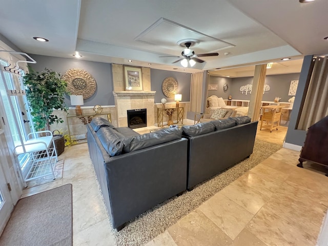 living room featuring ceiling fan and a fireplace