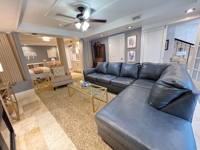 living room featuring ceiling fan and a raised ceiling